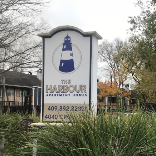 a sign with a tree and shrubbery