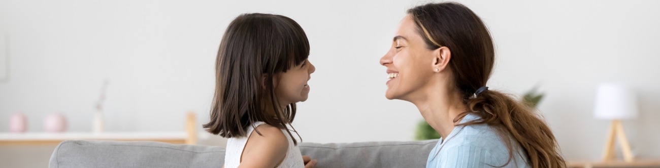 mom & daugther on couch looking at each other and smilaing